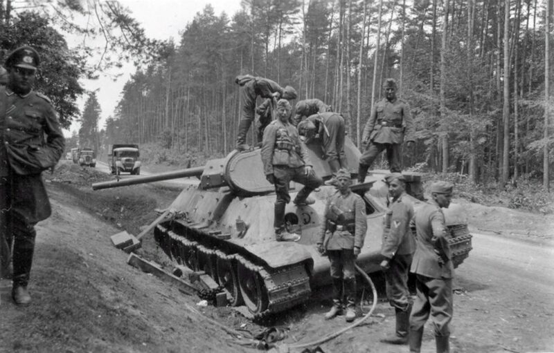 soldati tedeschi ispezionano il carro armato sovietico T-34 abbandonato sul lato della strada. 1941.